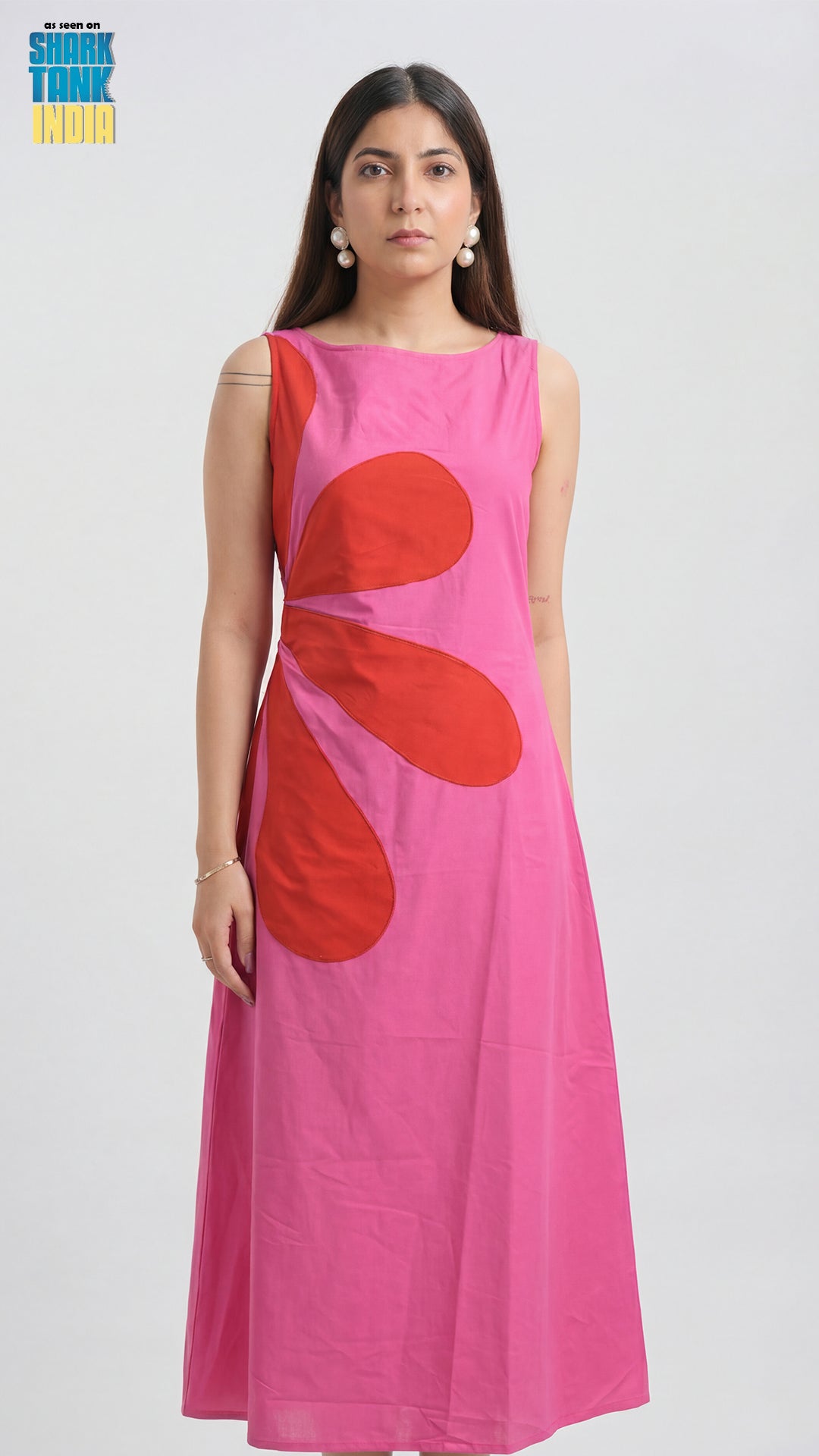 Woman wearing a pink dress with red floral patterns on a white background