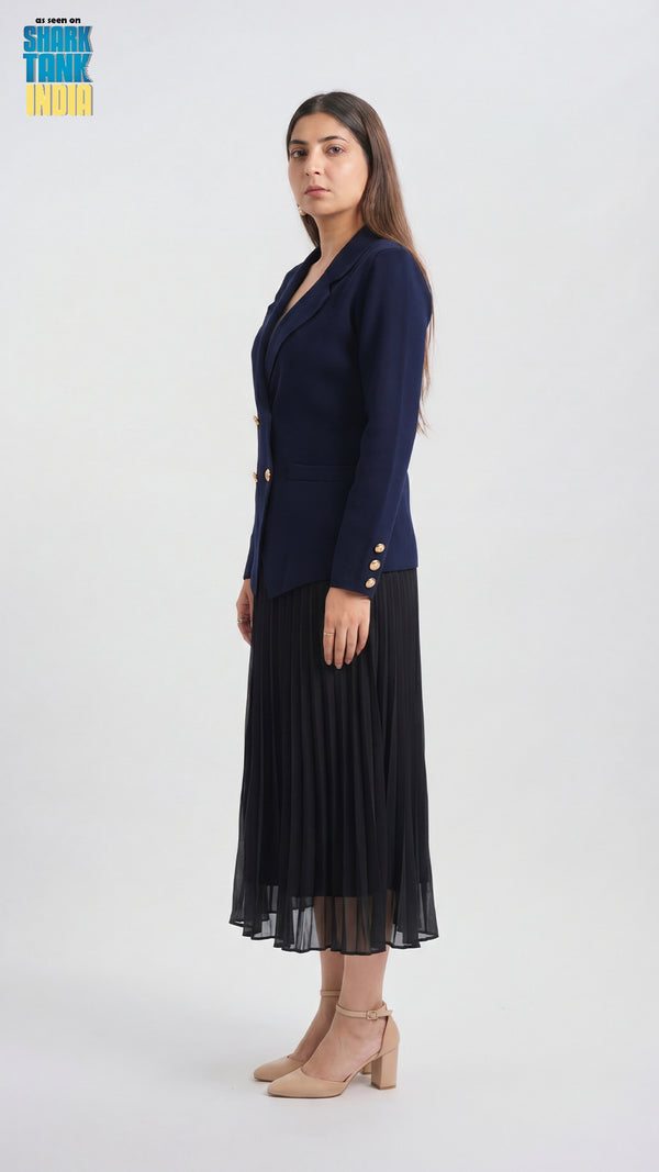 Woman wearing a navy blazer and black pleated skirt on a white background