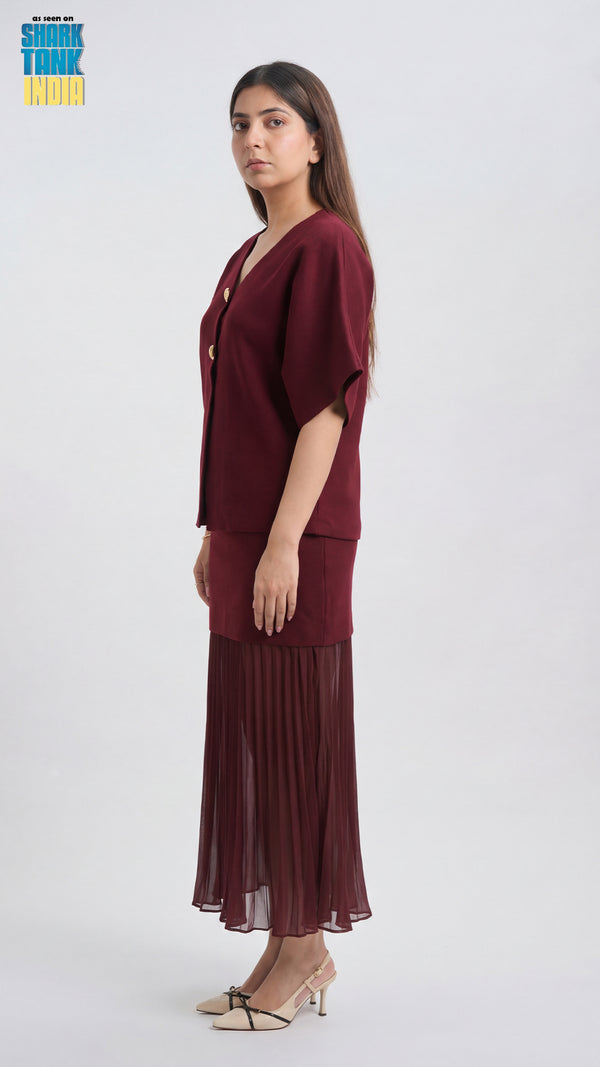 Woman wearing a burgundy outfit with a sheer overlay on a white background