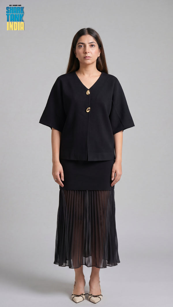 Woman wearing a black outfit with a sheer black skirt on a gray background