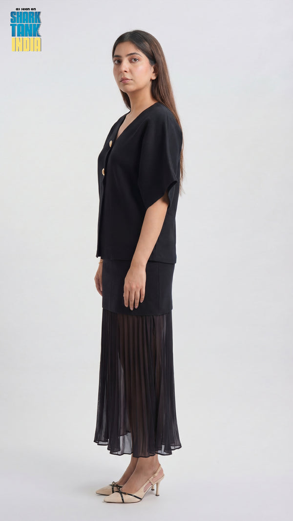 Woman wearing a black outfit with a pleated skirt on a white background