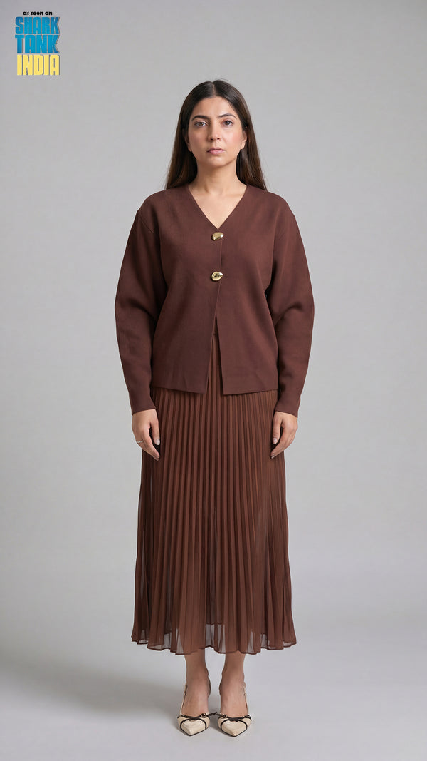 Woman wearing a brown cardigan and pleated skirt on a gray background