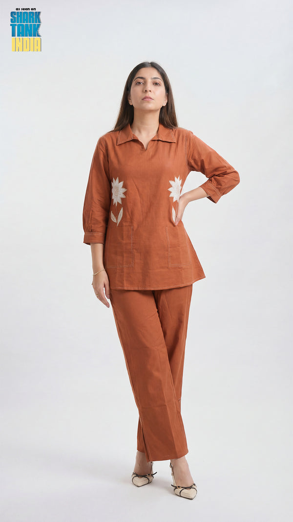 Woman wearing a brown outfit with floral designs on a white background