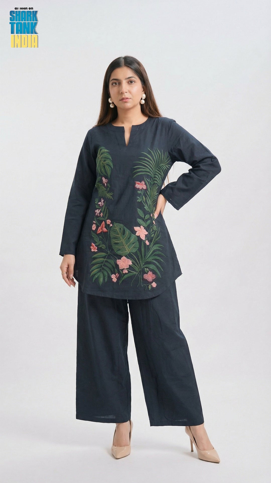 Woman wearing a dark blue outfit with floral embroidery on a white background