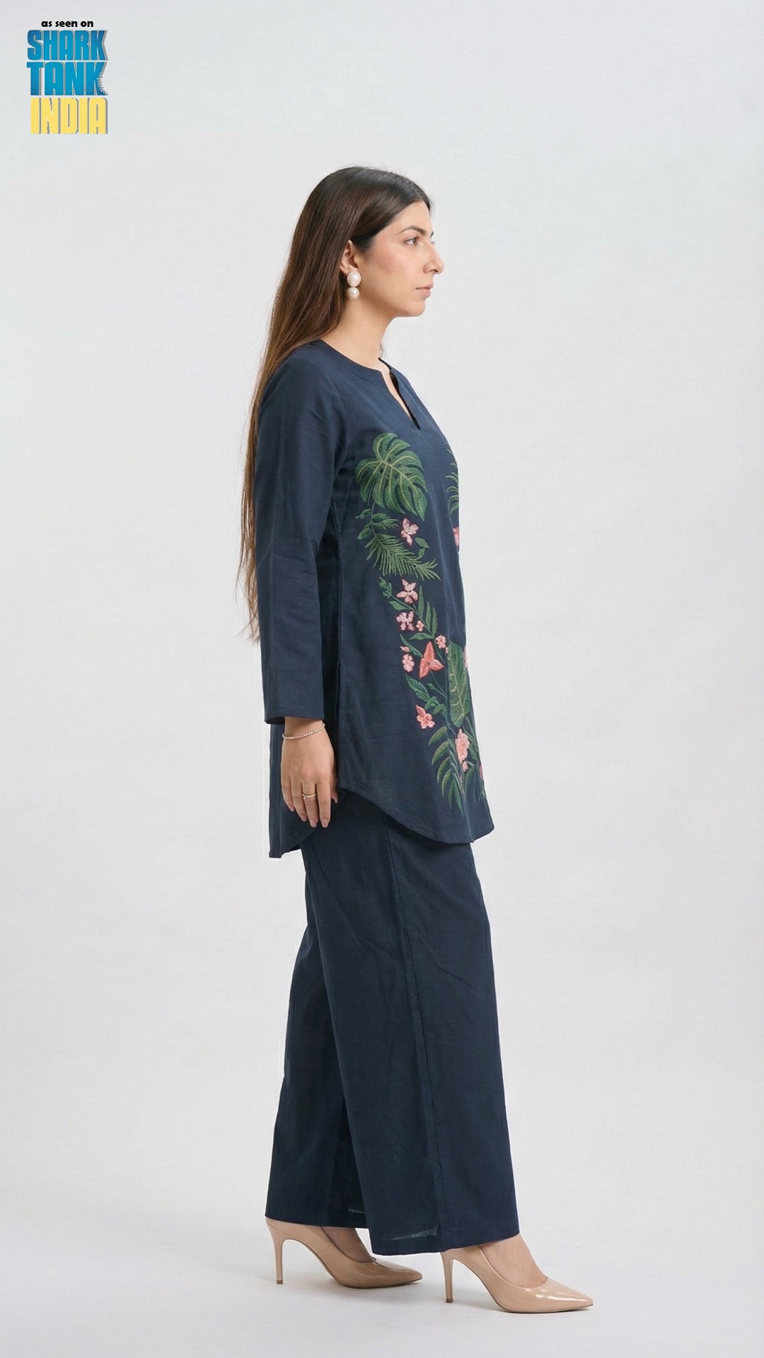 Woman wearing a navy blue outfit with floral embroidery on a white background