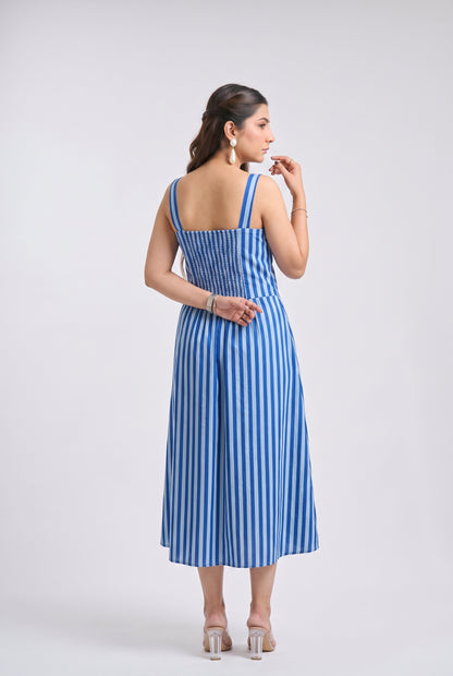 A woman modeling a blue and white vertically striped midi dress from the back, standing against a light gray studio background.