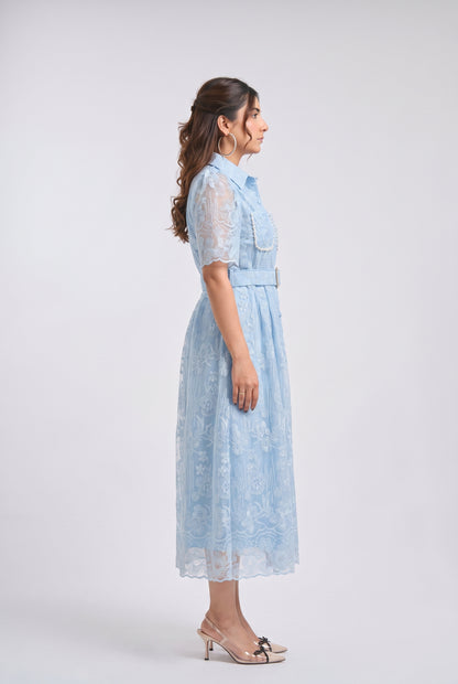 A woman modeling a light blue lace midi dress with short sleeves, a pointed collar, and a matching belt, shown in profile against a light gray studio background.