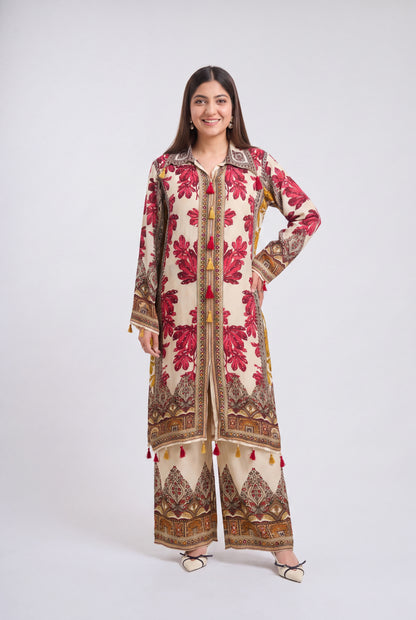 A woman modeling a traditional long kurta and wide-leg pants set in beige with red floral prints and brown geometric borders, photographed against a light gray studio background.