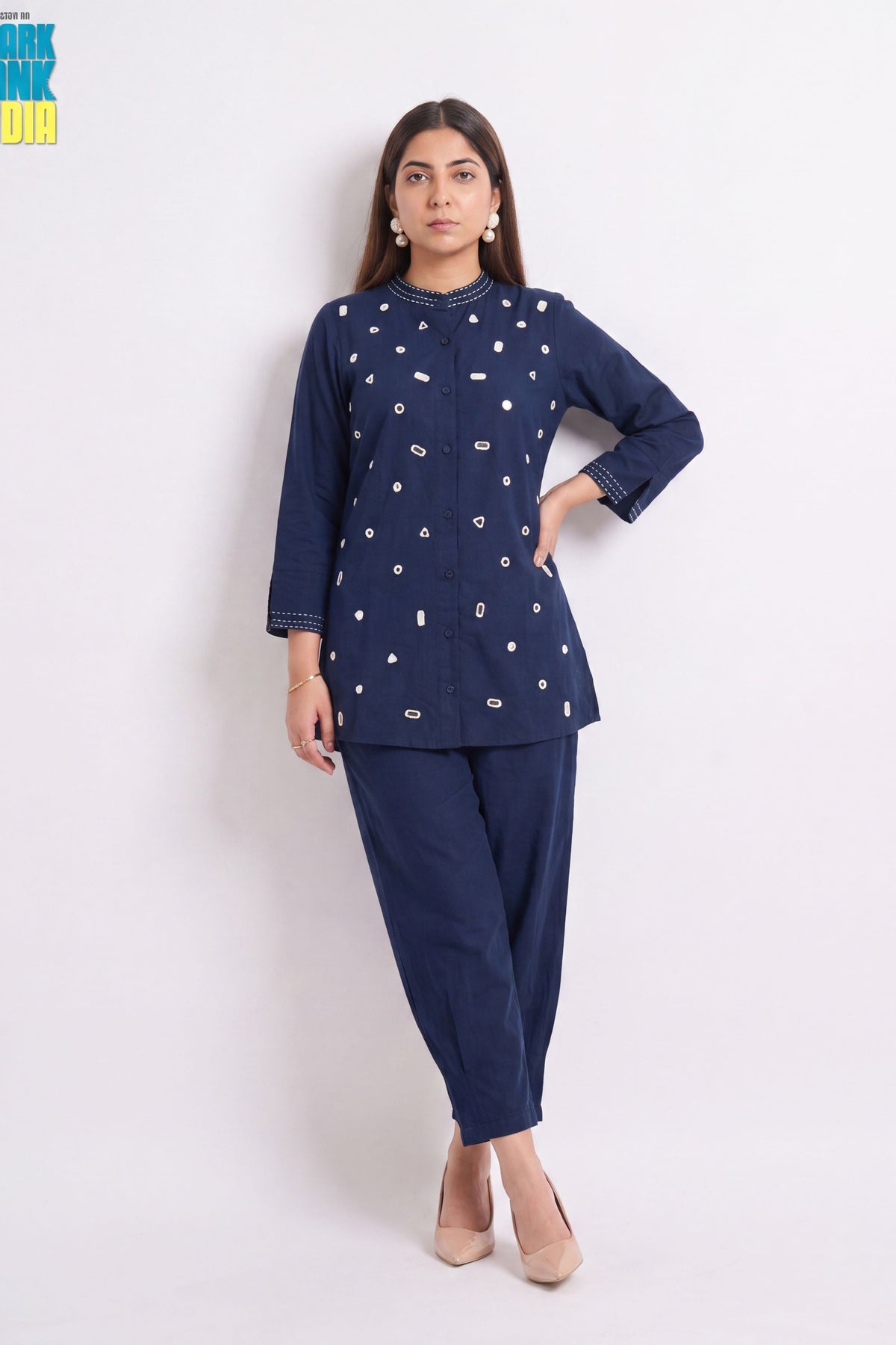 A woman modeling a navy blue kurta and trouser set with white embroidered details, standing against a plain white studio background.