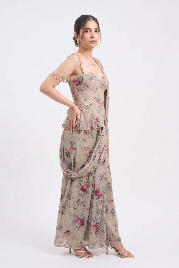 A woman modeling a beige floral off-the-shoulder maxi dress with a draped dupatta, standing against a plain white studio background.