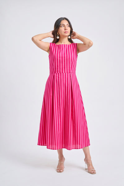 A woman modeling a sleeveless midi dress with vertical pink and white stripes, standing against a light gray studio background.