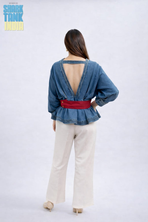 Woman wearing a denim top with an open back and red belt on a white background