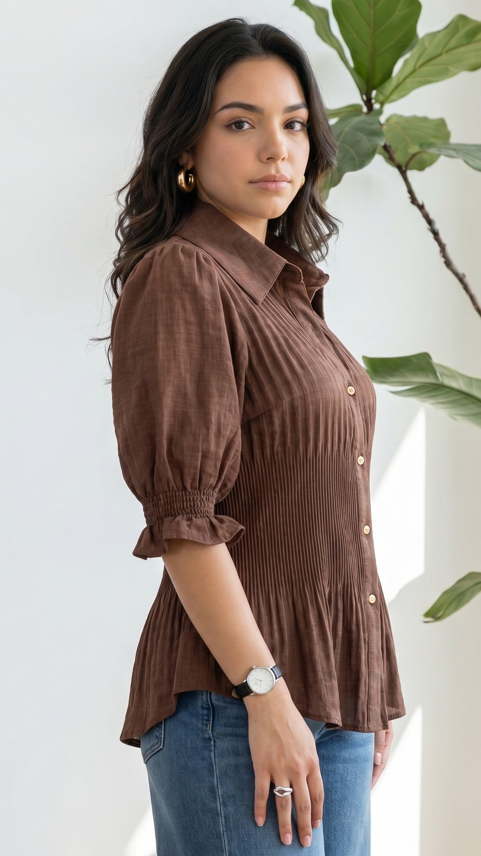 Woman wearing a brown ribbed blouse with puffed sleeves against a white background