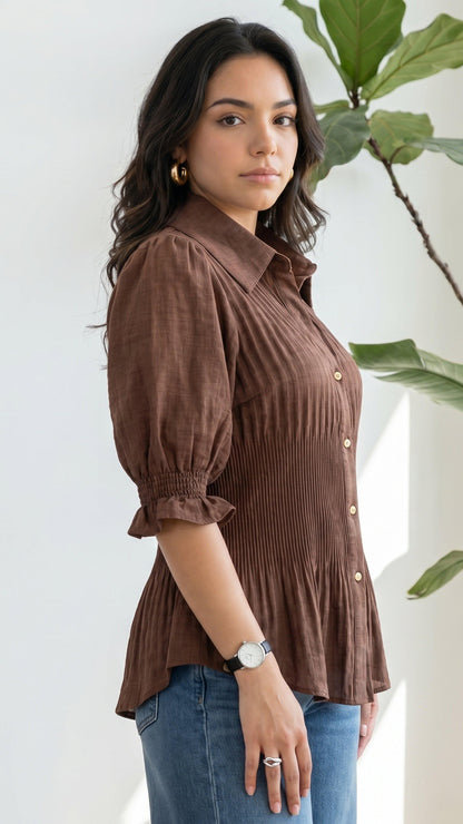 Woman wearing a brown ribbed blouse with puffed sleeves against a white background