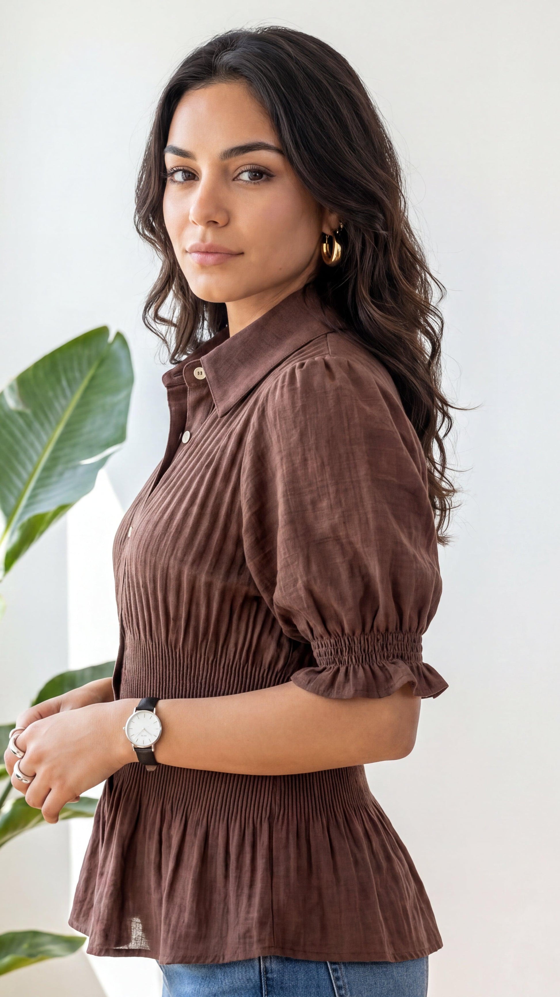 Woman wearing a brown blouse with puffed sleeves against a white background