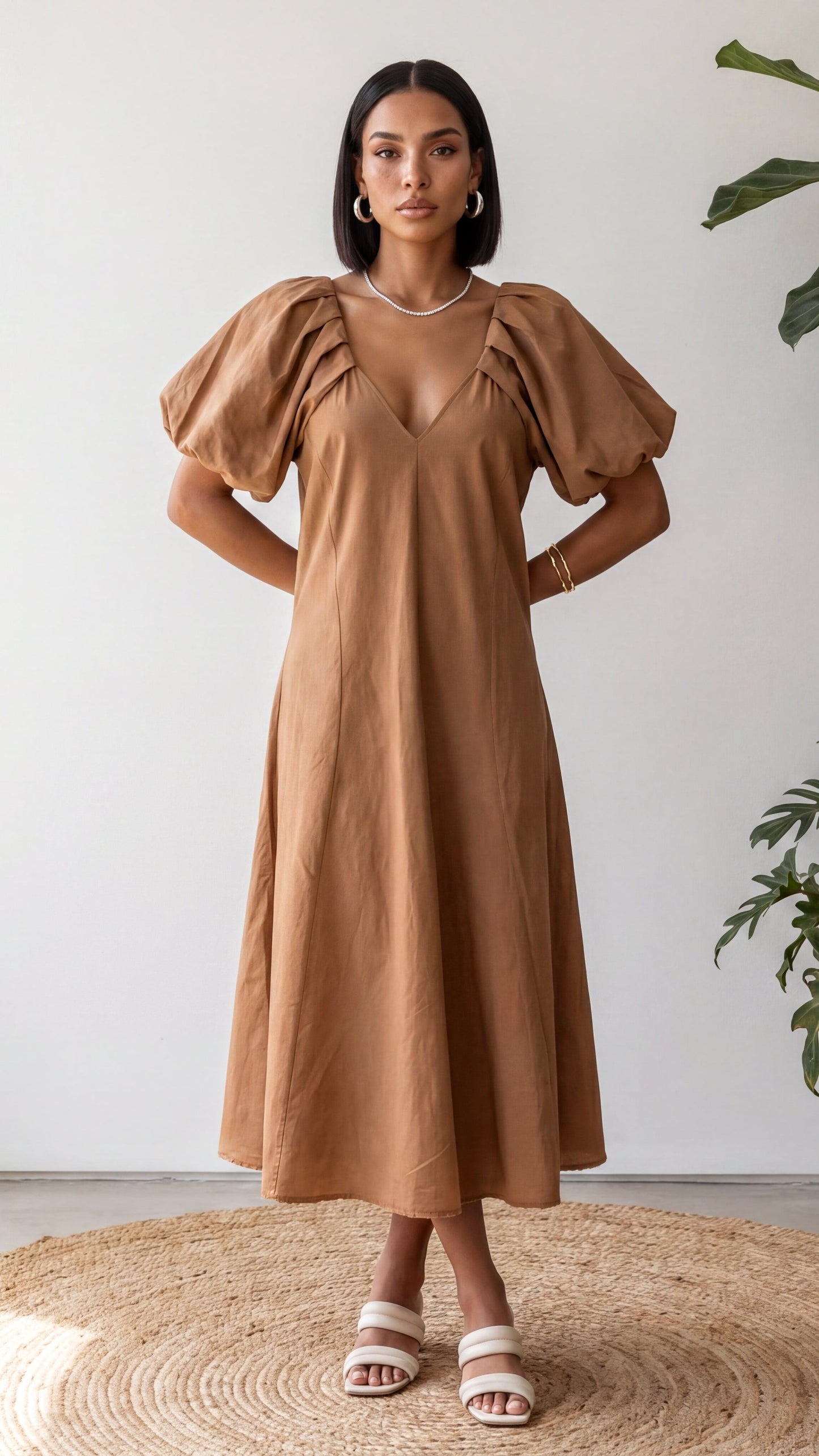 Woman wearing a brown dress with puff sleeves against a white background