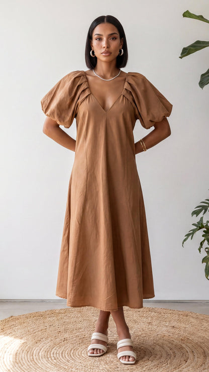 Woman wearing a brown dress with puff sleeves against a white background