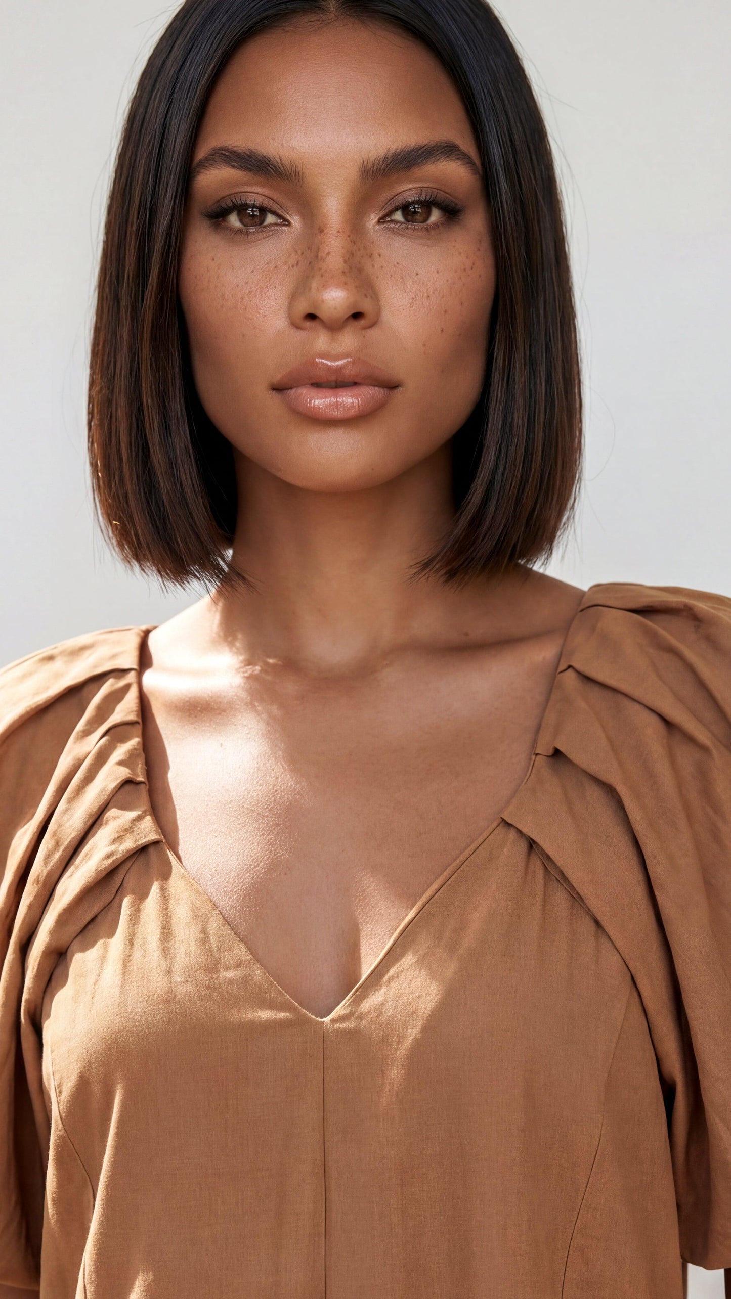 Woman wearing a brown top with a neutral background