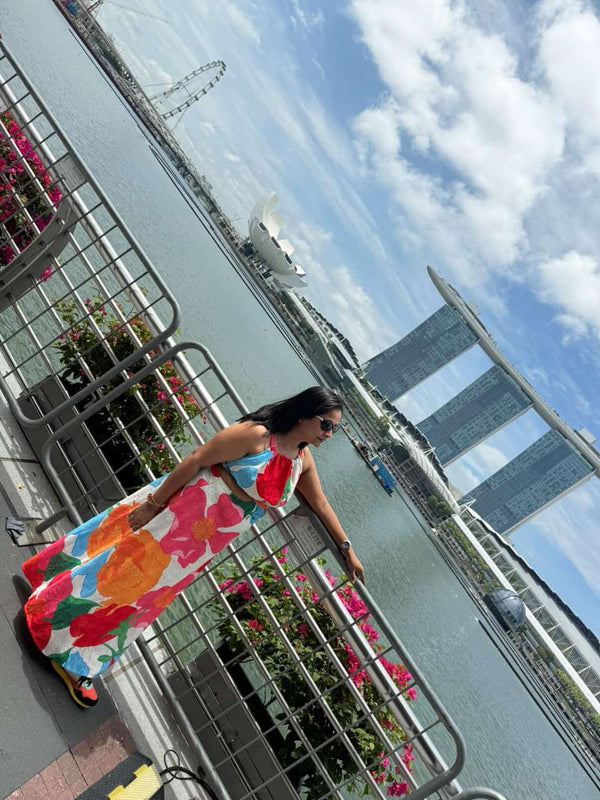 Woman in a colorful dress standing on a balcony with a cityscape in the background