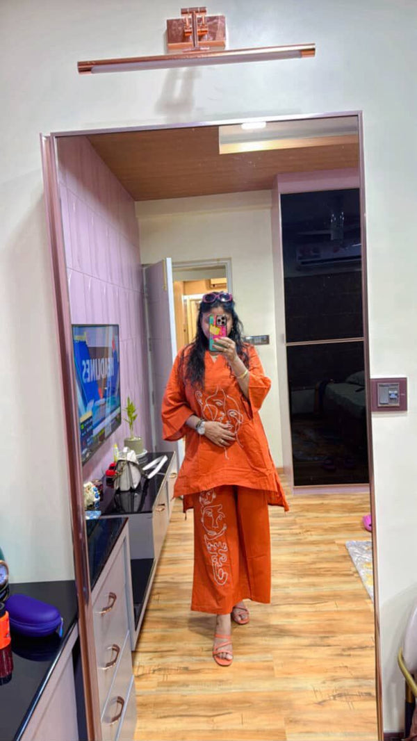 Person wearing an orange outfit standing in front of a mirror in a room.