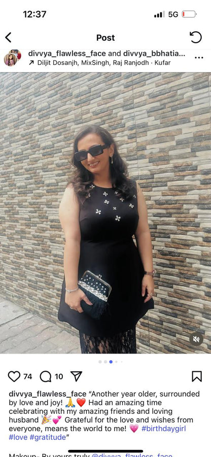 Woman in a black dress standing against a stone wall