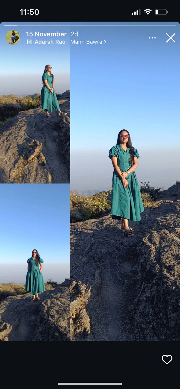 Woman in a green dress standing on a rocky outcrop with a scenic background.