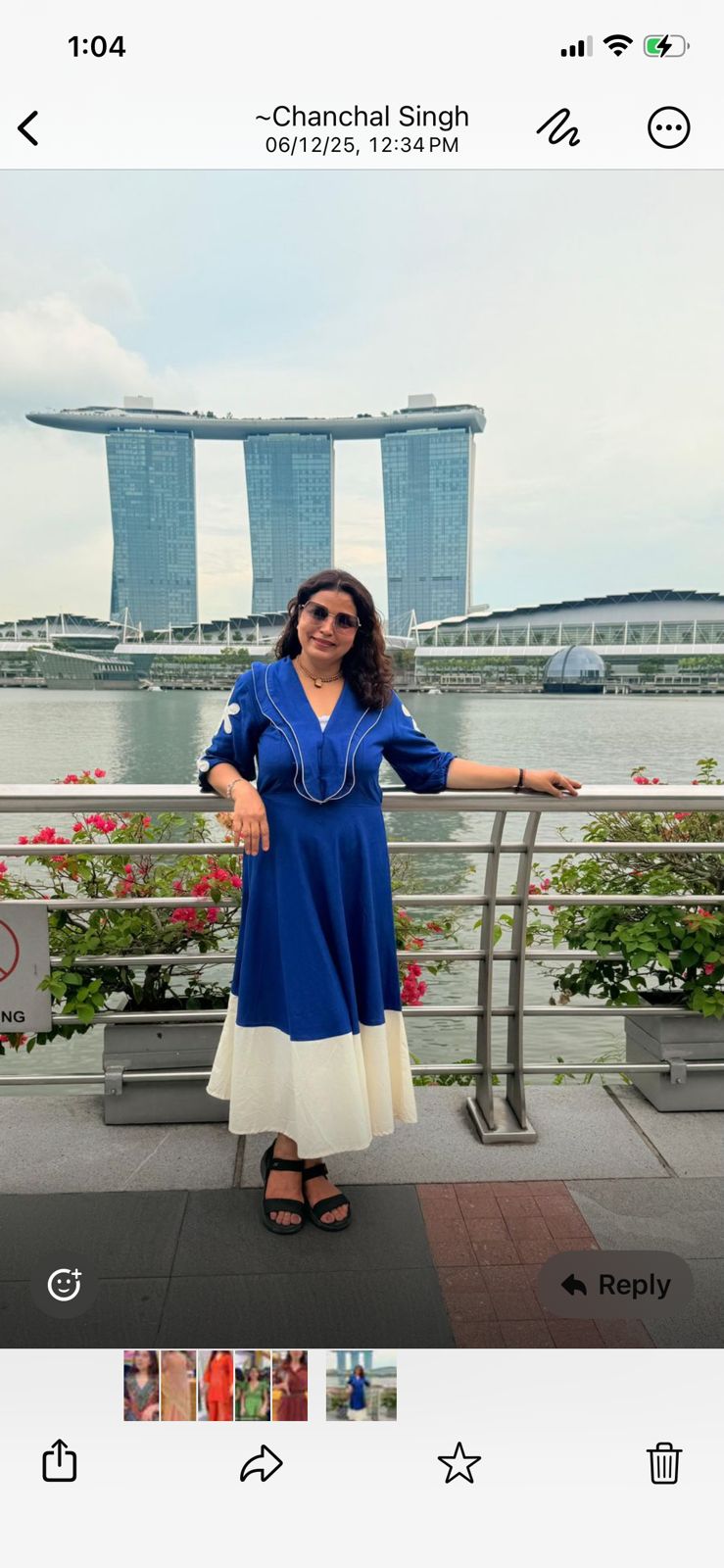 Woman in a blue dress standing on a balcony with the Marina Bay Sands in the background