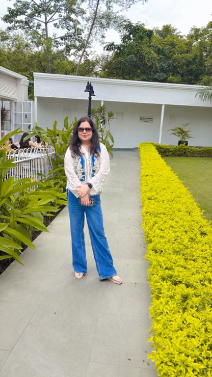 Woman standing on a path with greenery and a building in the background