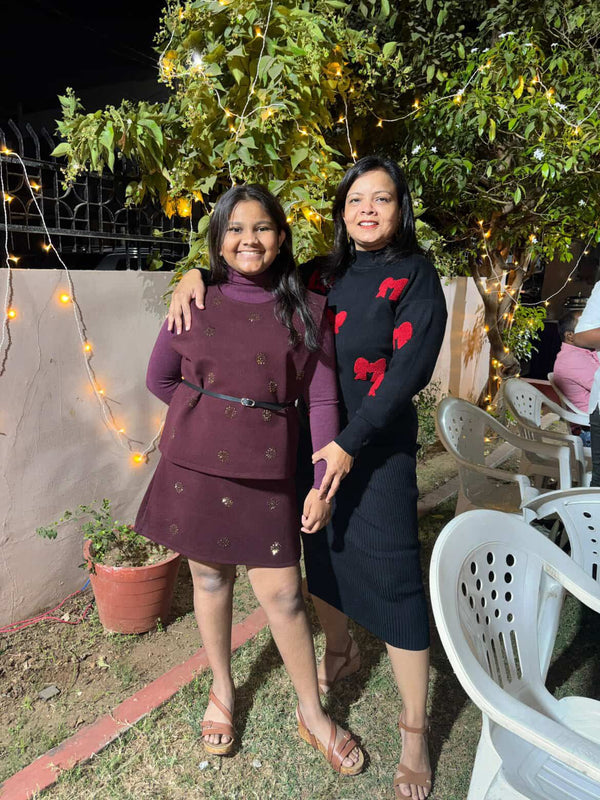 Two women standing together outdoors with string lights and a tree in the background
