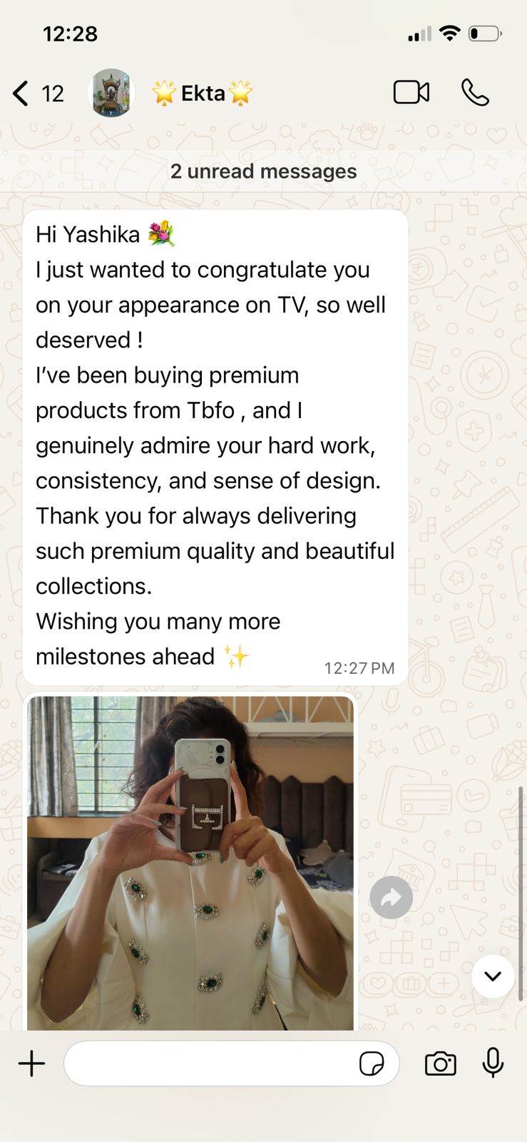 Text message congratulating someone on a TV appearance with a photo of a person holding a phone.