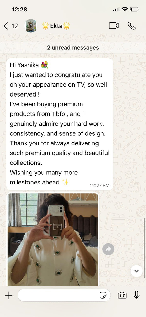 Text message congratulating someone on a TV appearance with a photo of a person holding a phone.