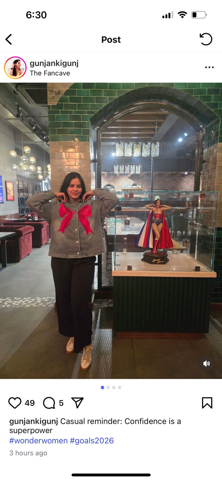 Person standing in a museum-like setting with a display case and statue.