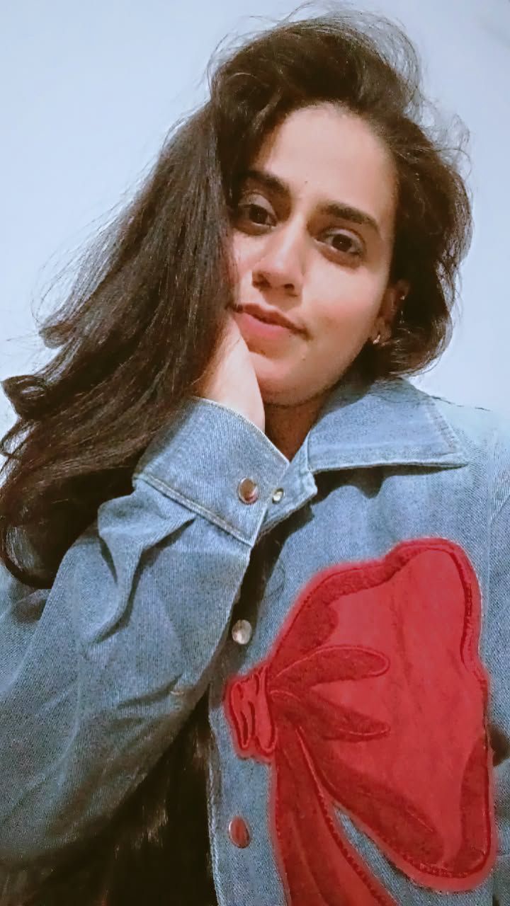 Person wearing a denim jacket with a red heart design on a light blue background