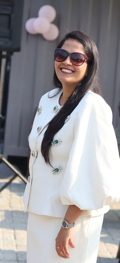 Woman in a white outfit with sunglasses standing outdoors