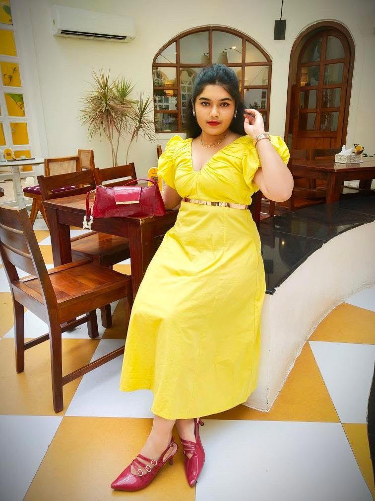 Woman in a yellow dress sitting at a dining table in a restaurant.