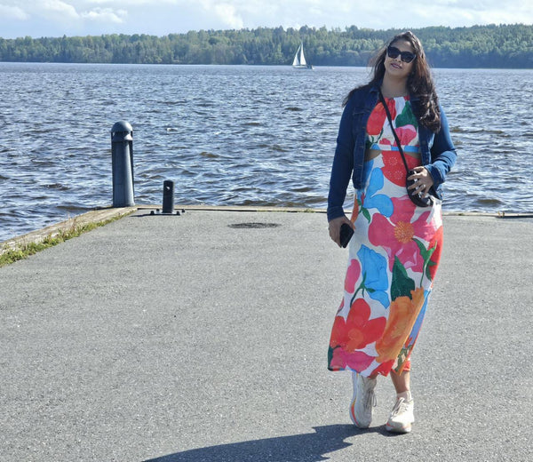 Woman in a colorful floral dress standing by a lake