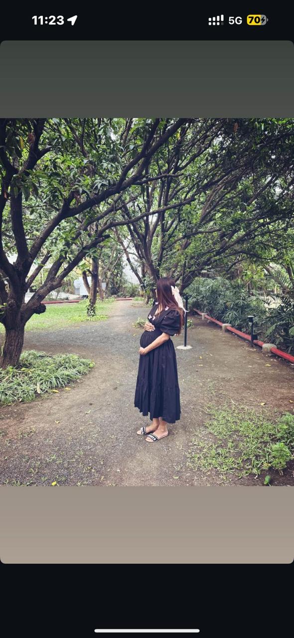 Woman in a black dress standing on a path surrounded by trees