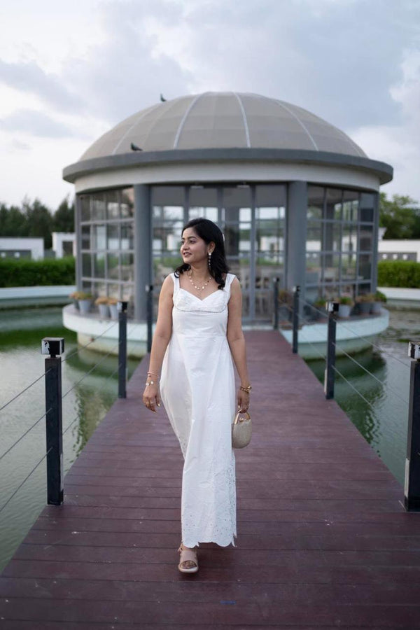 Woman in a white dress standing on a dock with a gazebo in the background