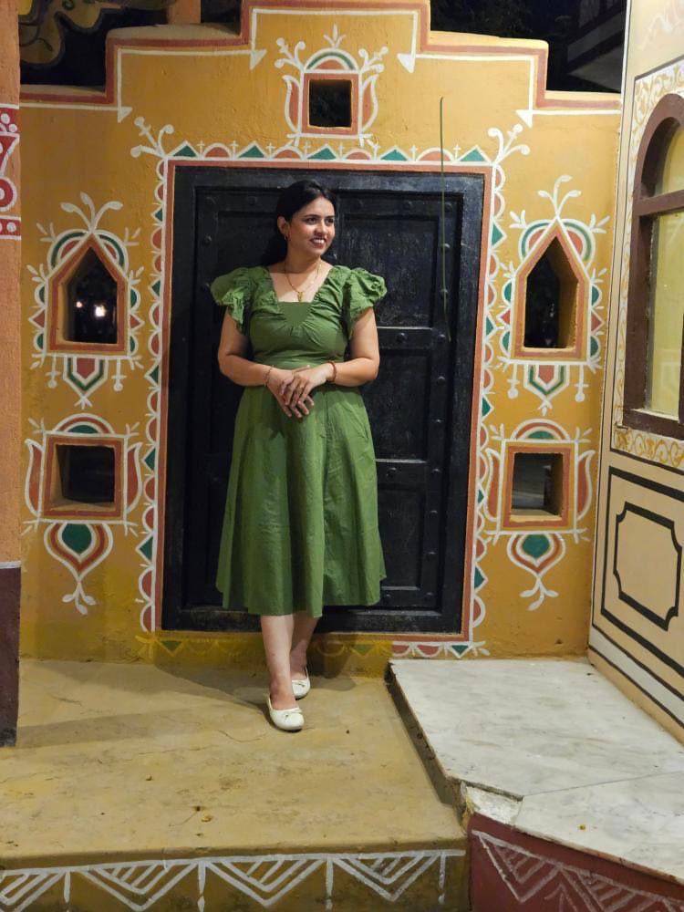 Woman in a green dress standing in front of a decorated door