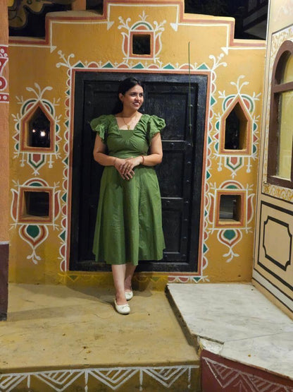 Woman in a green dress standing in front of a decorated door