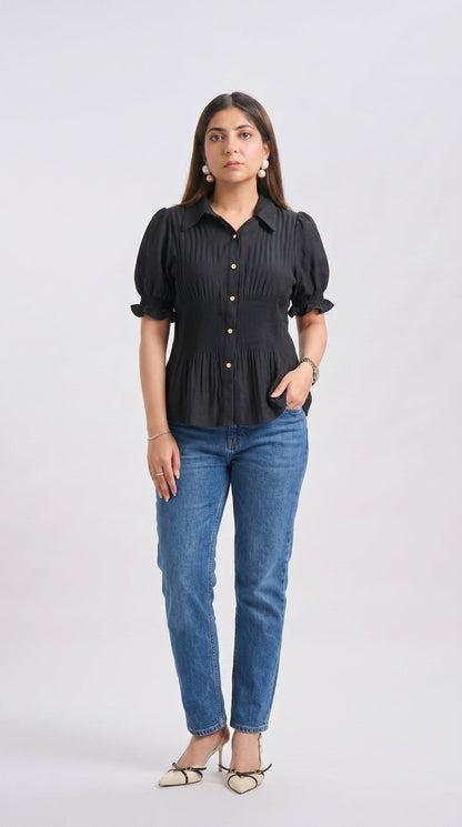 Woman wearing a black ruffled blouse and blue jeans on a white background