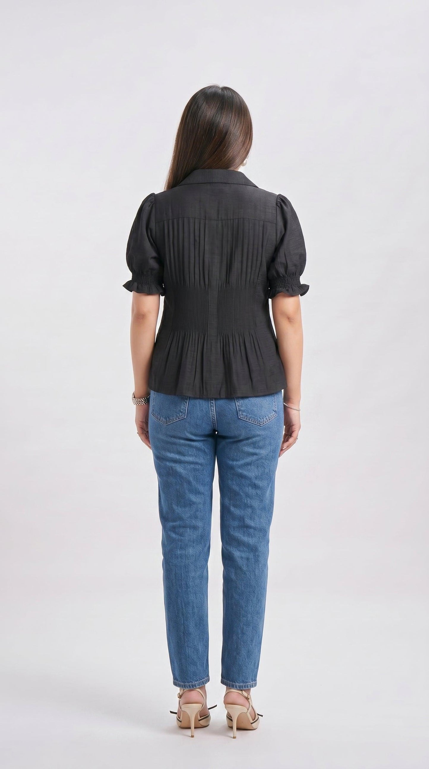 Woman wearing a black blouse and blue jeans on a white background