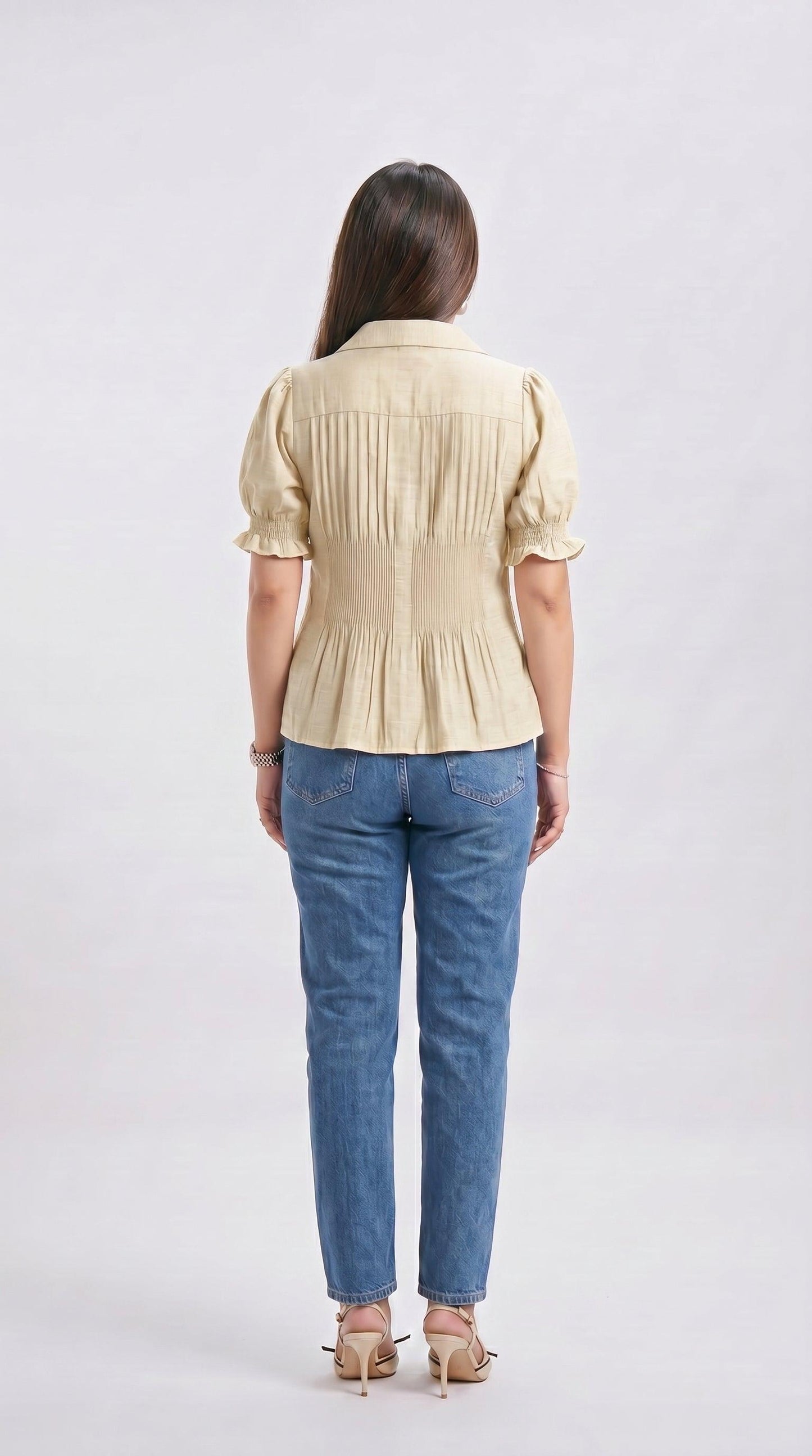 Woman wearing a beige blouse and blue jeans on a white background
