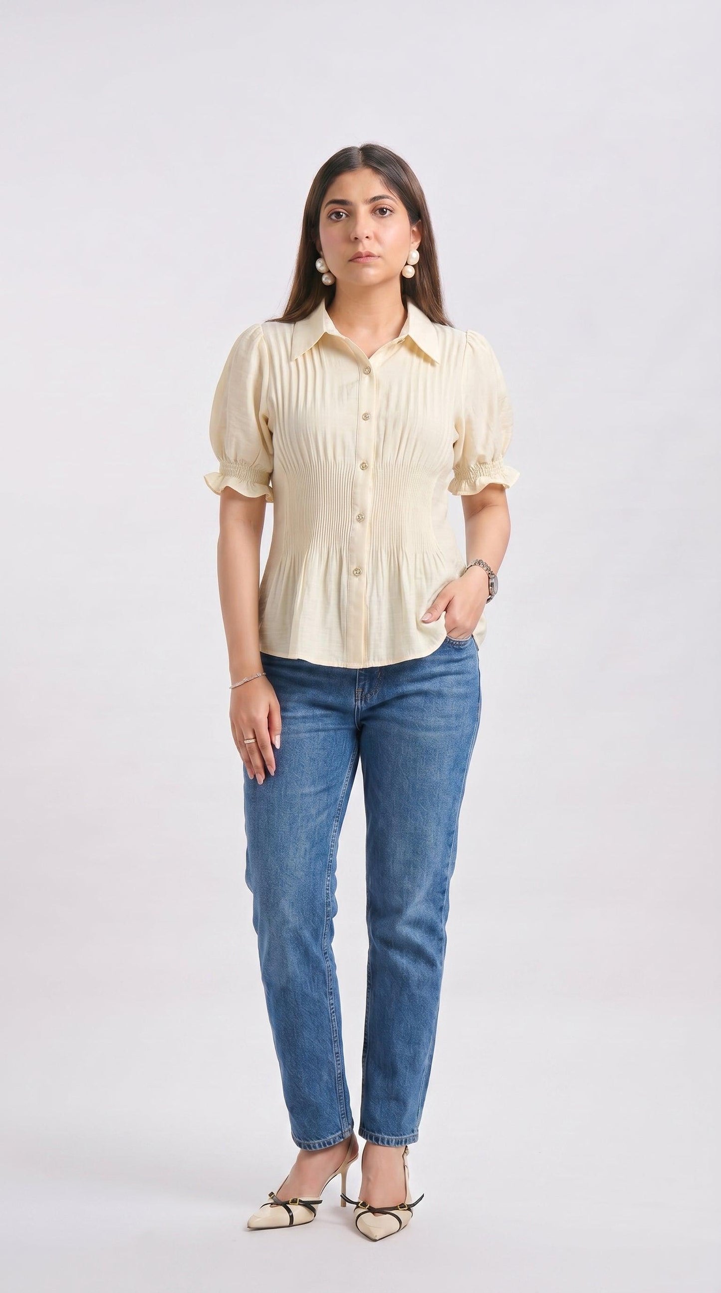 Woman wearing a light-colored blouse and blue jeans on a white background