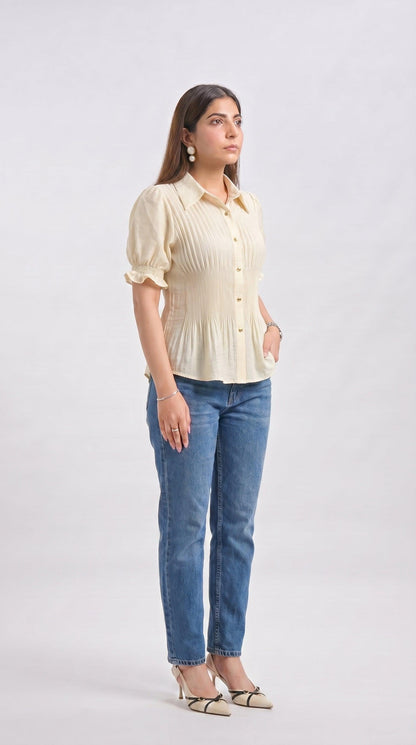 Woman wearing a light yellow blouse and blue jeans on a white background