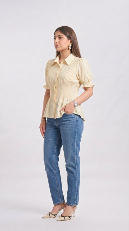 Woman wearing a light yellow blouse and blue jeans on a white background