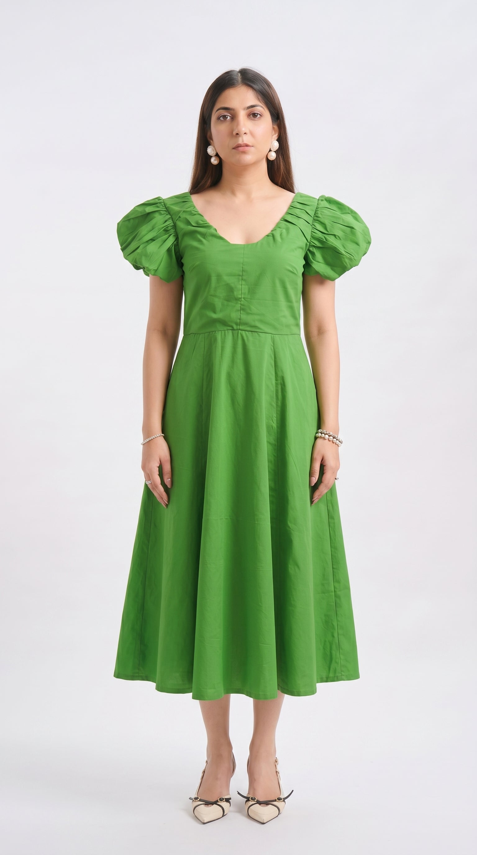 Woman wearing a green dress with puffed sleeves on a white background