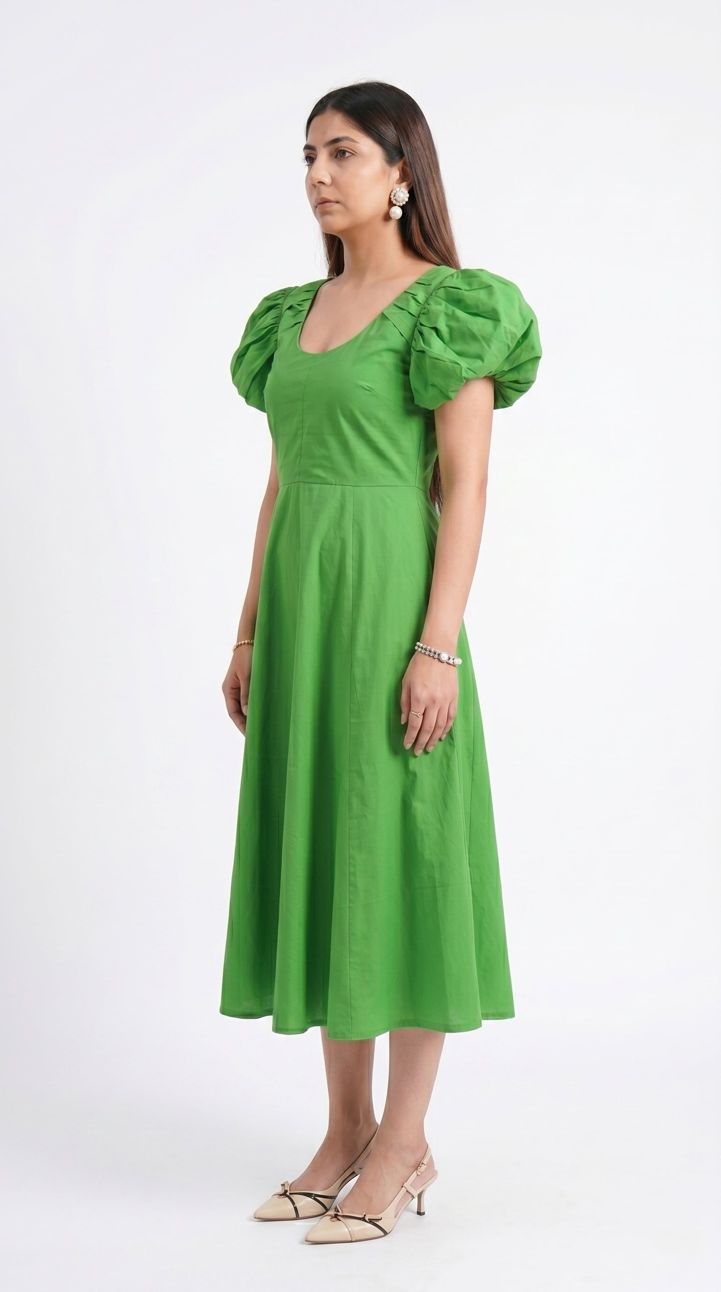 Woman wearing a green dress with puff sleeves on a white background