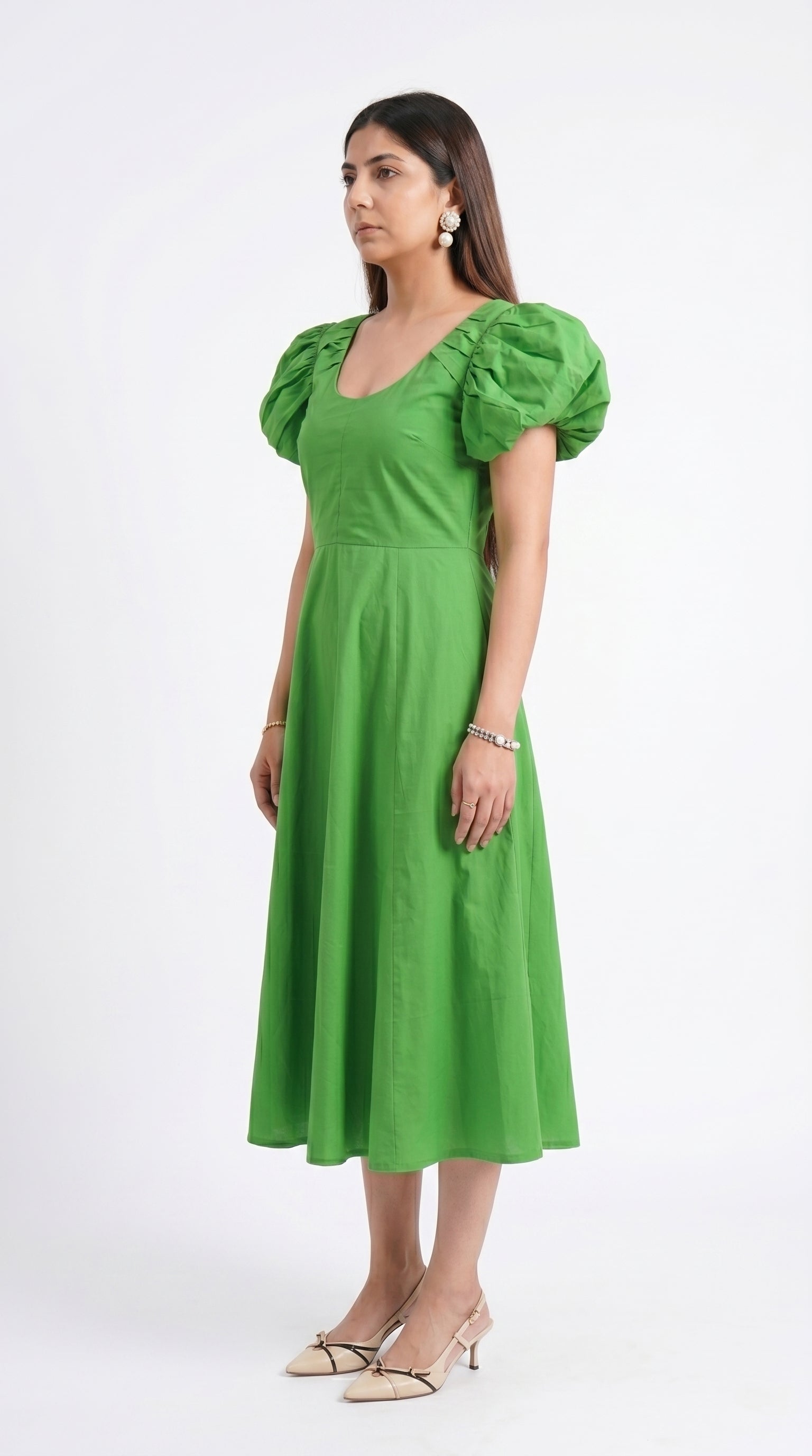 Woman wearing a green dress with puff sleeves on a white background