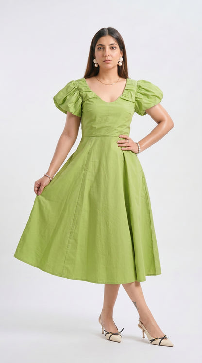 Woman wearing a green dress with puffed sleeves on a white background